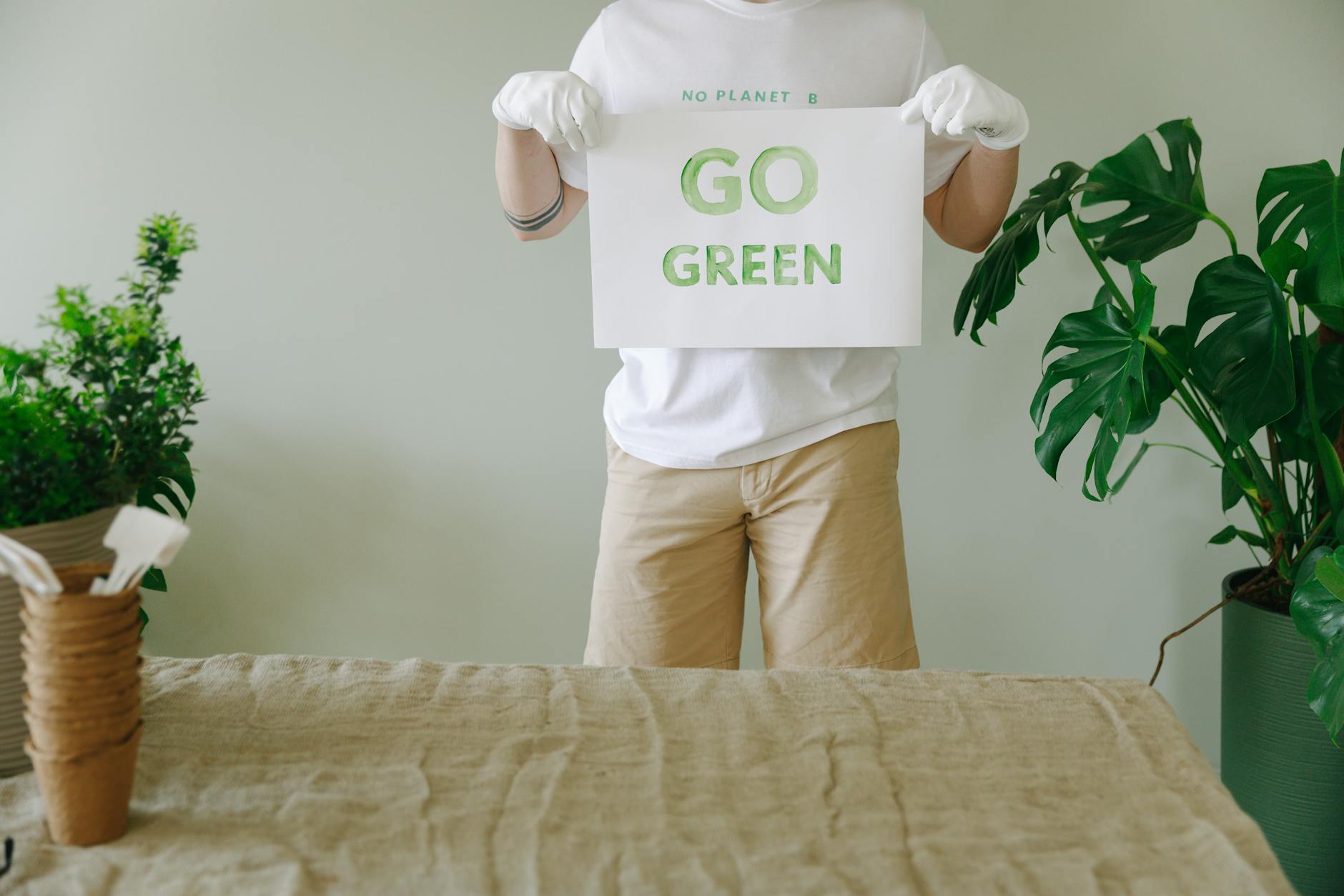person in white t shirt and brown pants holding a slogan with go green text